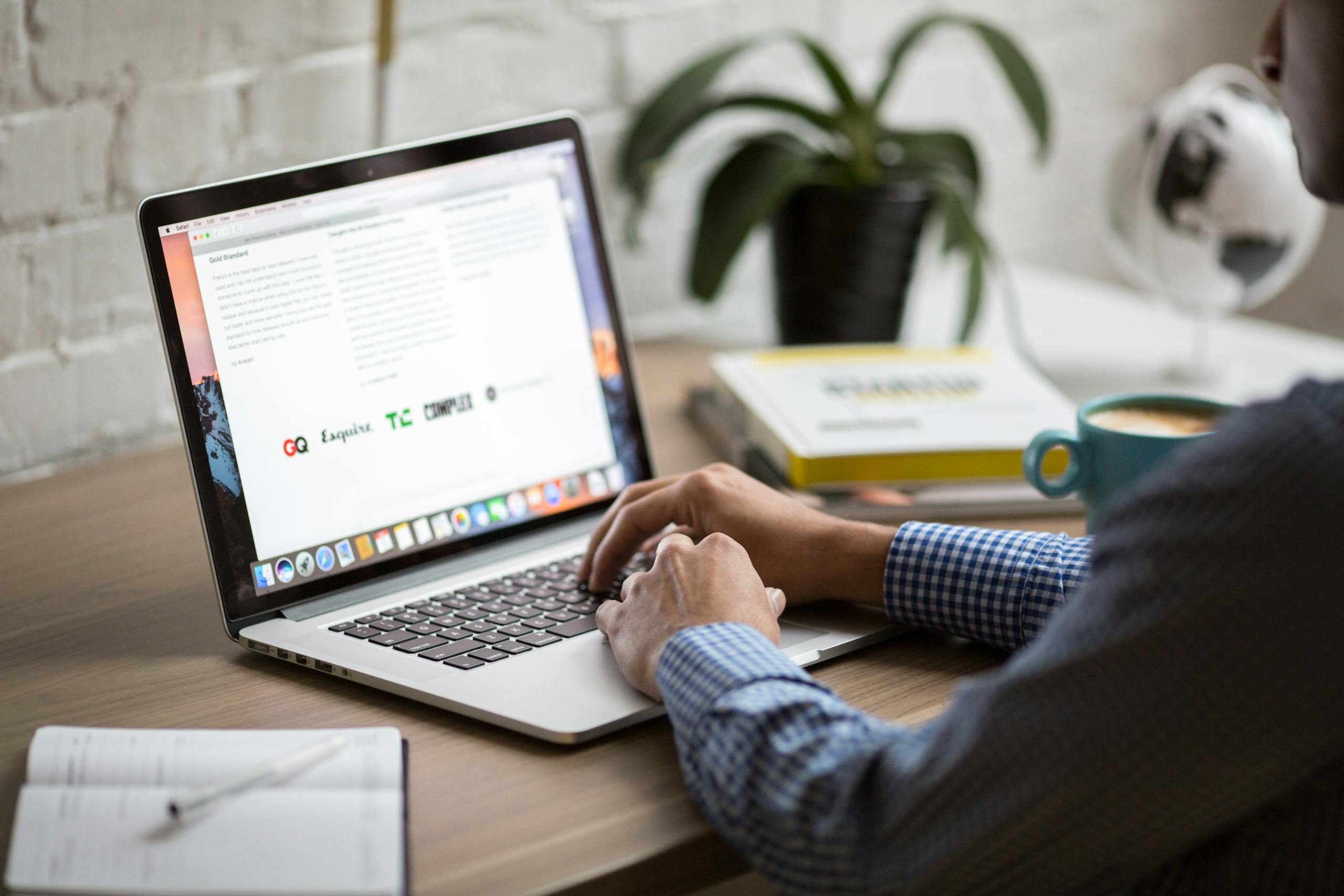Home 1 Web design services - A man working on a laptop at a desk with coffee, showcasing remote work in a modern office setting.
